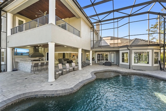 pool featuring an outdoor kitchen, a lanai, a patio area, outdoor dry bar, and an outdoor hangout area