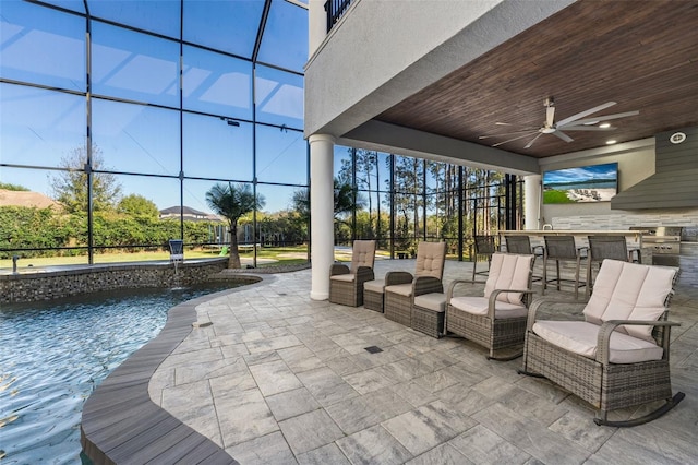 view of patio / terrace featuring outdoor dry bar, glass enclosure, area for grilling, an outdoor pool, and a ceiling fan