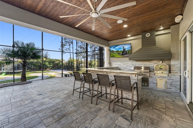 view of patio featuring area for grilling, glass enclosure, a grill, and outdoor wet bar