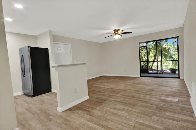 spare room featuring light wood-style flooring, baseboards, and ceiling fan