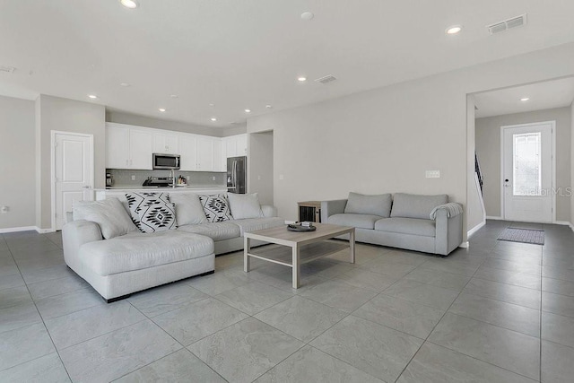living room with baseboards, visible vents, and recessed lighting