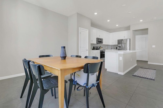 tiled dining area featuring baseboards and recessed lighting