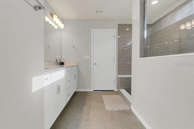 full bath featuring vanity, baseboards, visible vents, and walk in shower