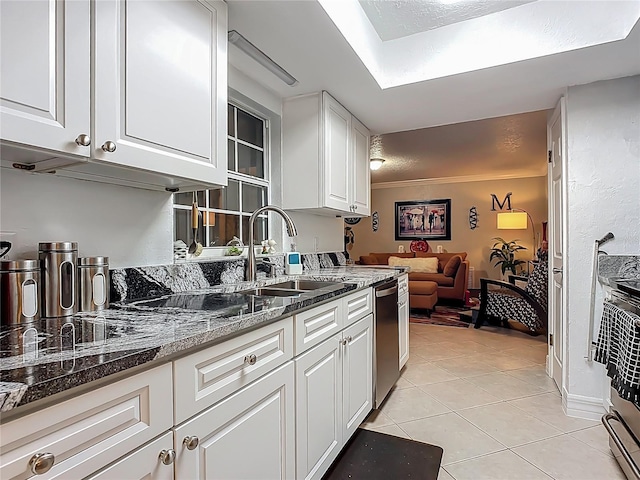 kitchen featuring light tile patterned floors, dark stone counters, a sink, white cabinets, and appliances with stainless steel finishes