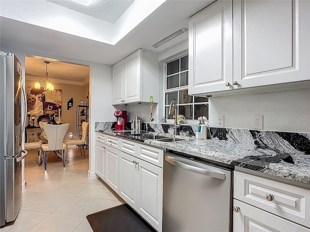 kitchen with light tile patterned floors, a sink, ornamental molding, stainless steel appliances, and white cabinets