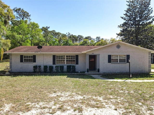 ranch-style home featuring stucco siding and a front lawn