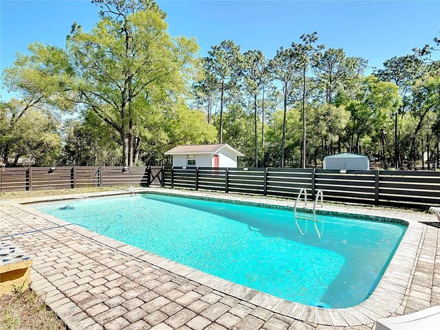 view of swimming pool featuring an outdoor structure, a fenced in pool, fence, and a patio