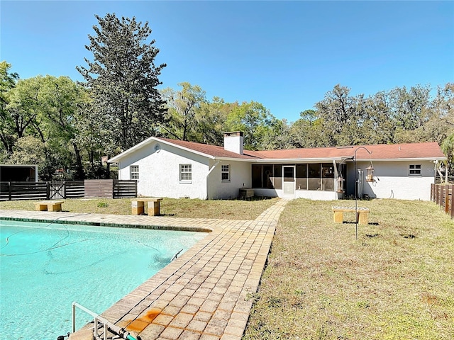 back of property with stucco siding, fence, a yard, and a sunroom