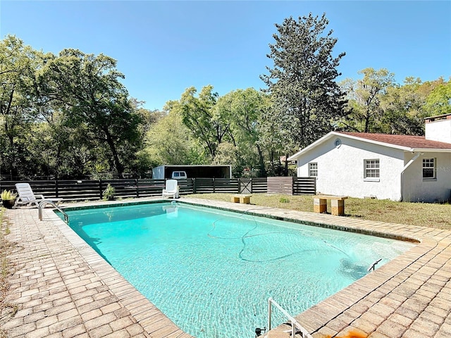 view of swimming pool featuring an outbuilding, fence, and a fenced in pool