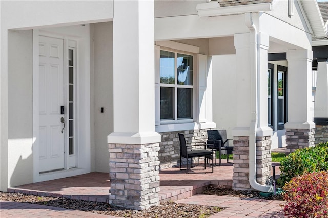 entrance to property featuring stone siding and a porch