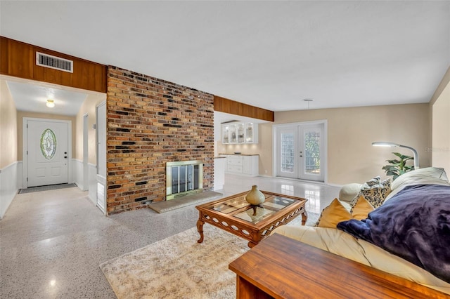 living area with visible vents, french doors, speckled floor, and a brick fireplace