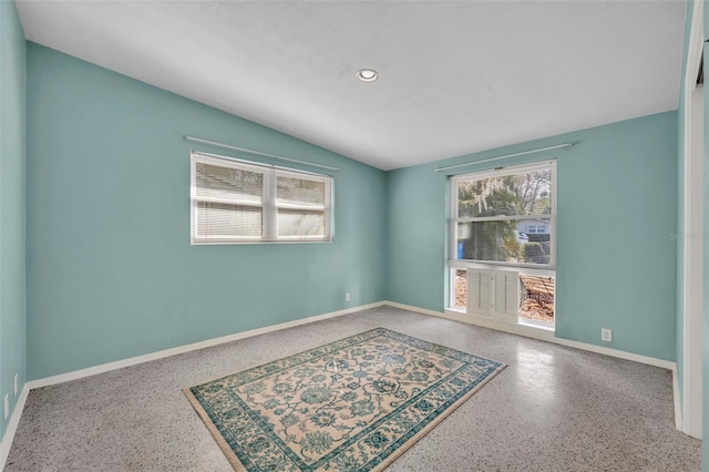 spare room featuring recessed lighting, speckled floor, baseboards, and vaulted ceiling