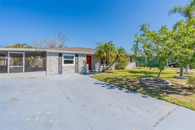 view of front of home with a carport, stone siding, concrete driveway, and a front yard