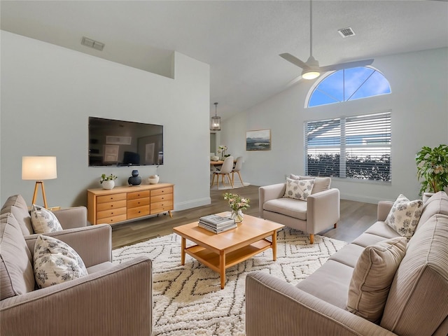 living room with baseboards, wood finished floors, visible vents, and ceiling fan