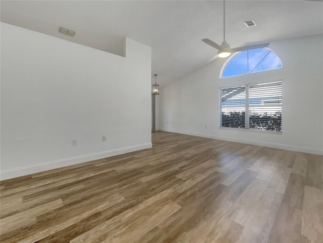 unfurnished living room with visible vents, baseboards, vaulted ceiling, wood finished floors, and a ceiling fan