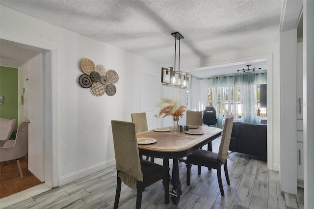 dining room with a textured ceiling, baseboards, and wood tiled floor