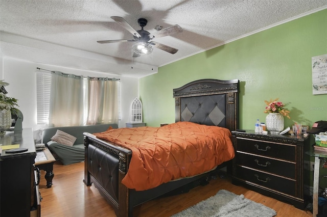 bedroom with a textured ceiling, wood finished floors, ceiling fan, and ornamental molding