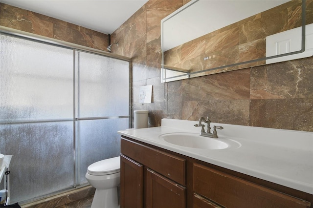 full bathroom featuring toilet, tile walls, a stall shower, and vanity