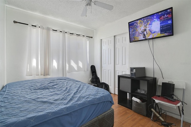 bedroom with a closet, a textured ceiling, wood finished floors, and a ceiling fan