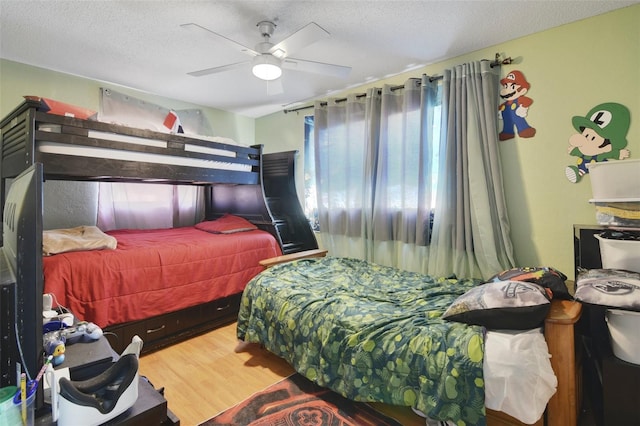 bedroom featuring a textured ceiling, ceiling fan, and wood finished floors