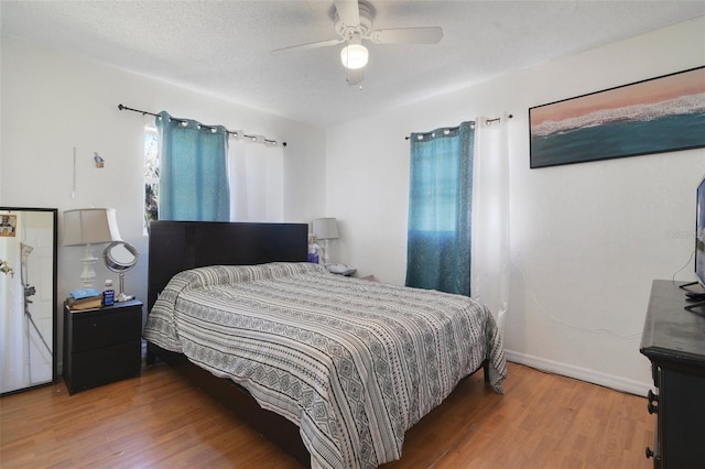 bedroom featuring ceiling fan, baseboards, a textured ceiling, and wood finished floors