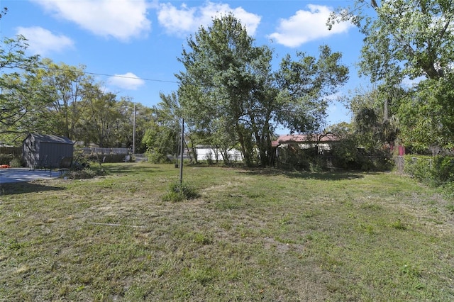 view of yard featuring a shed, an outdoor structure, and fence