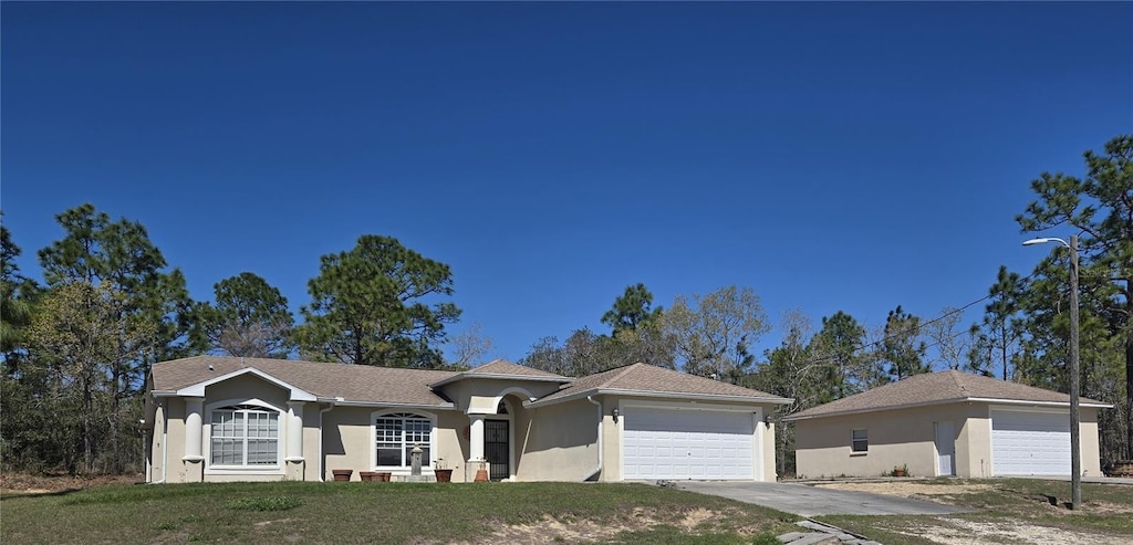 view of front facade featuring stucco siding, concrete driveway, a garage, and a front yard