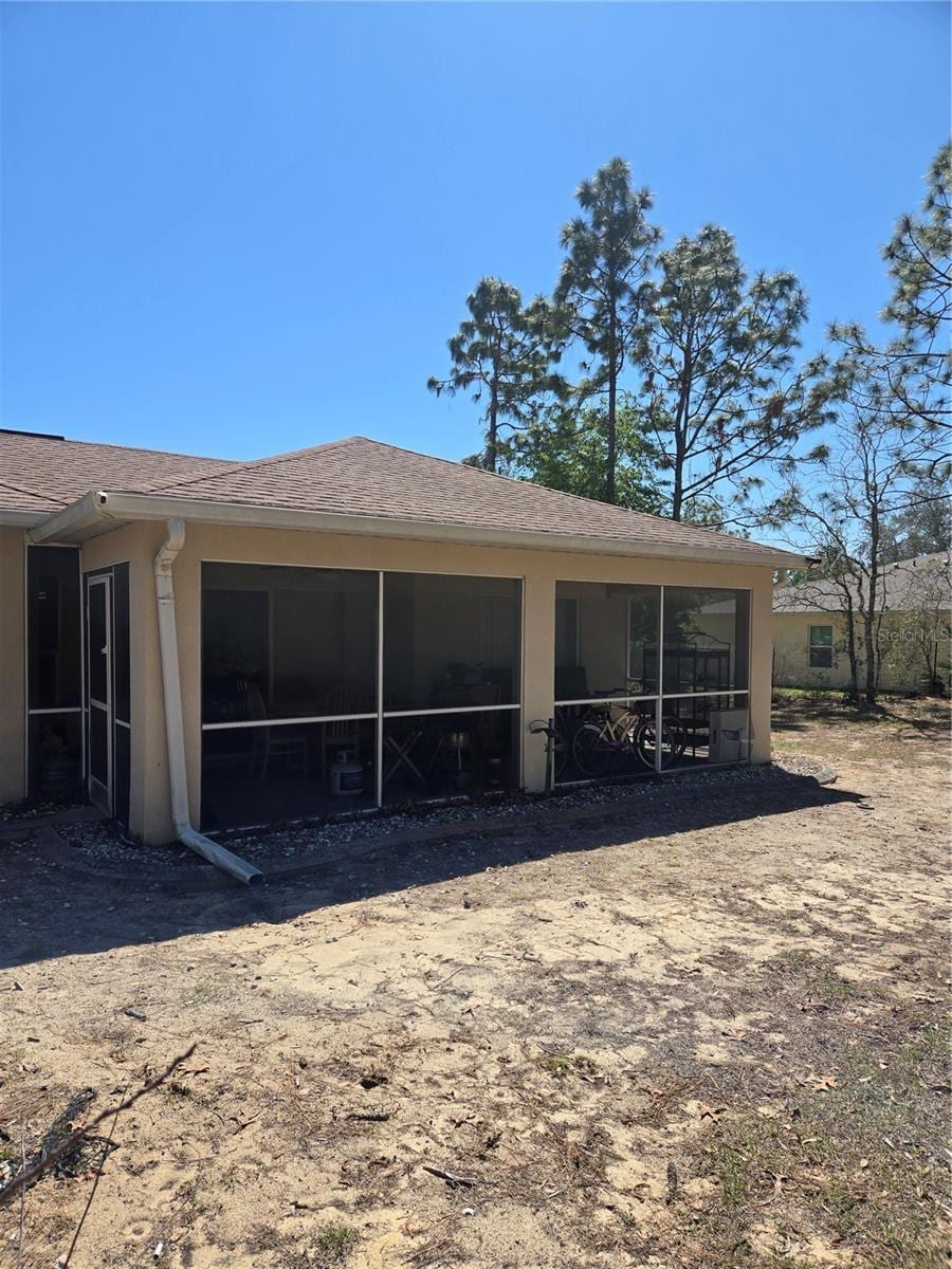 rear view of house with a sunroom and stucco siding