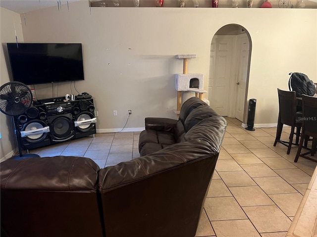 living room featuring baseboards, arched walkways, and light tile patterned flooring