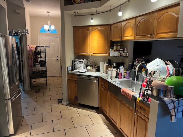 kitchen featuring track lighting, brown cabinetry, appliances with stainless steel finishes, and a sink