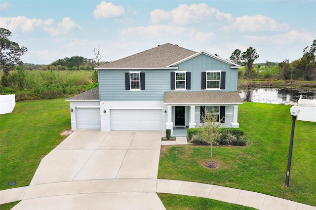 traditional-style home featuring driveway, roof with shingles, a front yard, and a water view