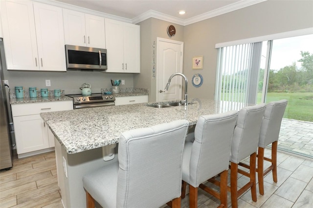 kitchen featuring a sink, a kitchen island with sink, white cabinetry, and stainless steel appliances