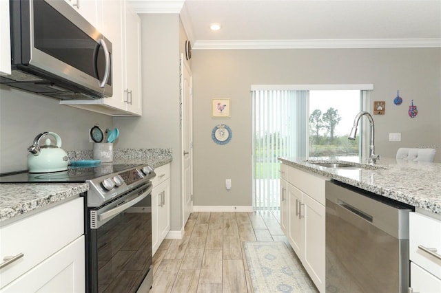 kitchen with a sink, light stone counters, stainless steel appliances, white cabinets, and wood tiled floor