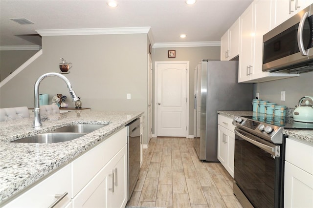 kitchen featuring visible vents, a sink, stainless steel appliances, white cabinets, and crown molding