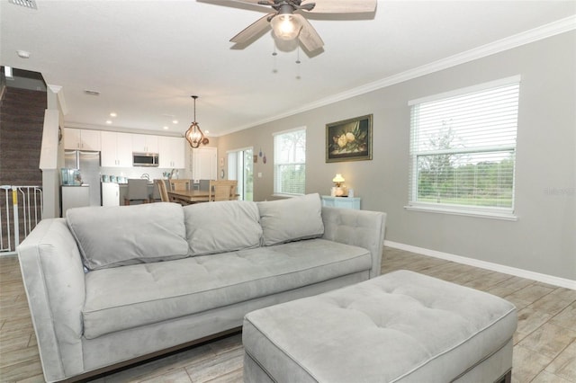 living room with baseboards, light wood-style floors, a healthy amount of sunlight, and crown molding