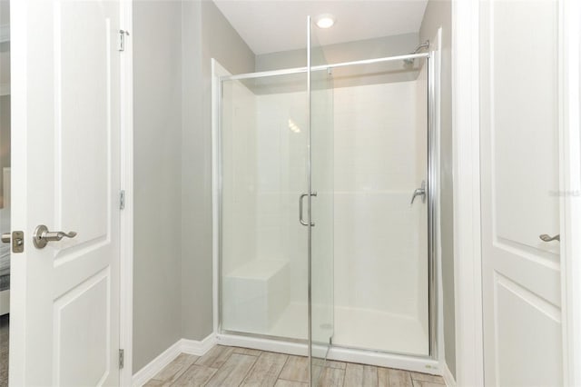 full bath with baseboards, a stall shower, and wood tiled floor