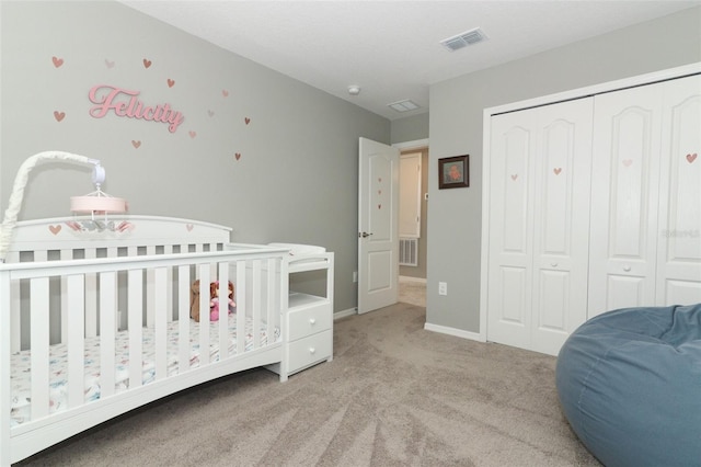 carpeted bedroom with a closet, visible vents, baseboards, and a nursery area