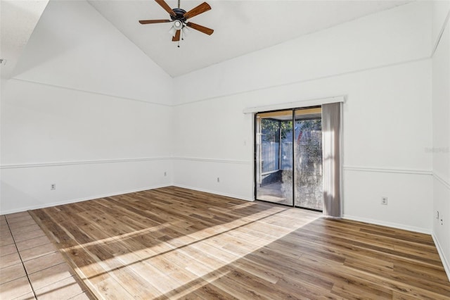 empty room with high vaulted ceiling, wood finished floors, baseboards, and ceiling fan