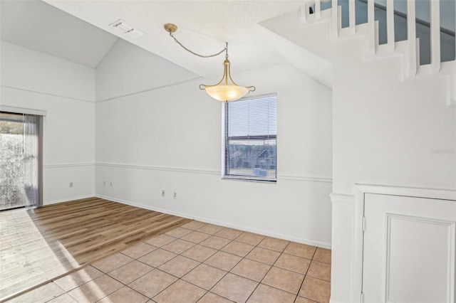 unfurnished room with lofted ceiling, light wood-style floors, visible vents, and baseboards