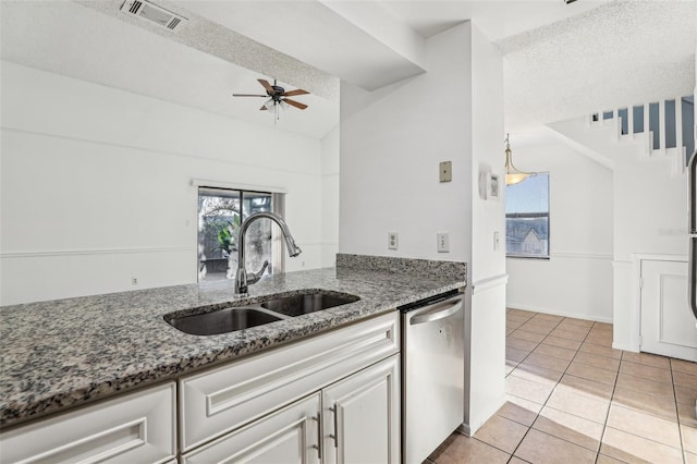 kitchen featuring visible vents, dishwasher, light tile patterned floors, stone counters, and a sink