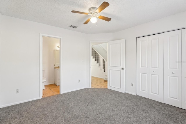 unfurnished bedroom with visible vents, a closet, a textured ceiling, light colored carpet, and connected bathroom