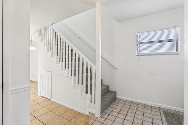 stairway with tile patterned flooring, a textured ceiling, and baseboards