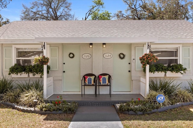 property entrance featuring a porch and a shingled roof