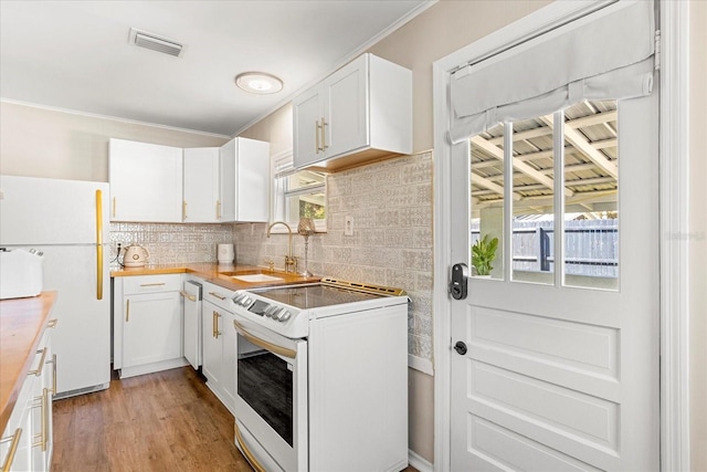 kitchen with visible vents, light wood-type flooring, a sink, backsplash, and white appliances