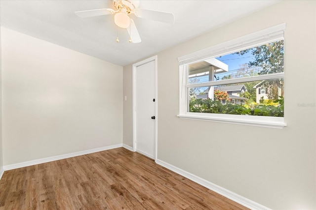 unfurnished room featuring baseboards, wood finished floors, and a ceiling fan