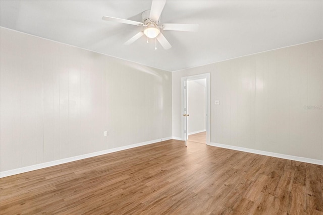 empty room featuring baseboards, wood finished floors, and a ceiling fan