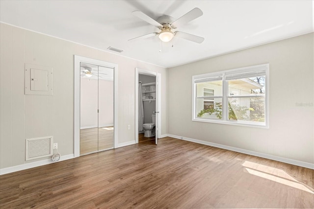 unfurnished bedroom featuring visible vents, baseboards, electric panel, wood finished floors, and a ceiling fan