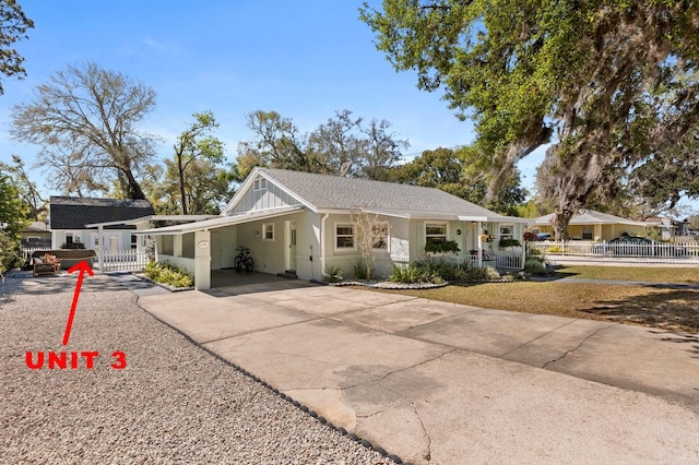 view of front of house with an attached carport, board and batten siding, driveway, and fence