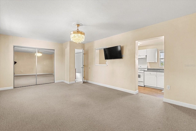 interior space with an inviting chandelier, light colored carpet, and baseboards