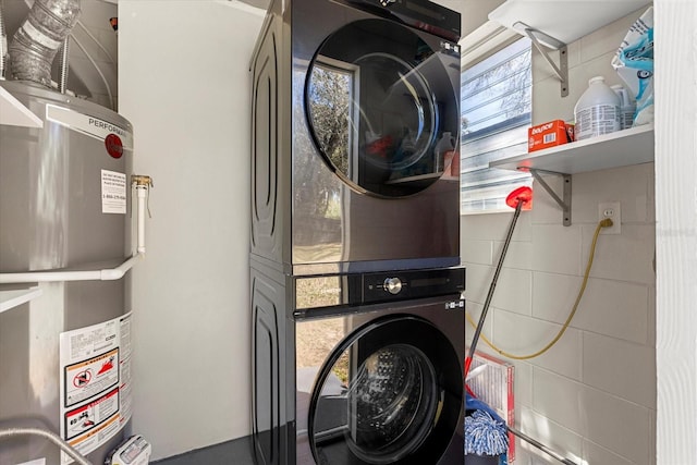 clothes washing area with laundry area, secured water heater, and stacked washing maching and dryer